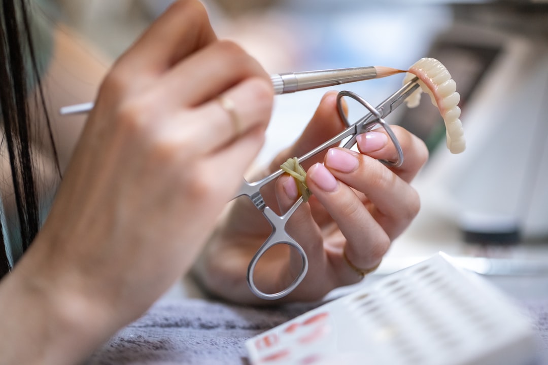 Close-up of a dental technician working on a prosthetic denture using precision tools. We are happy for using this photo on your site.
